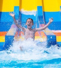 Happy,Cheerful,Boy,Splashing,Water,On,Water,Slide,At,Aqua